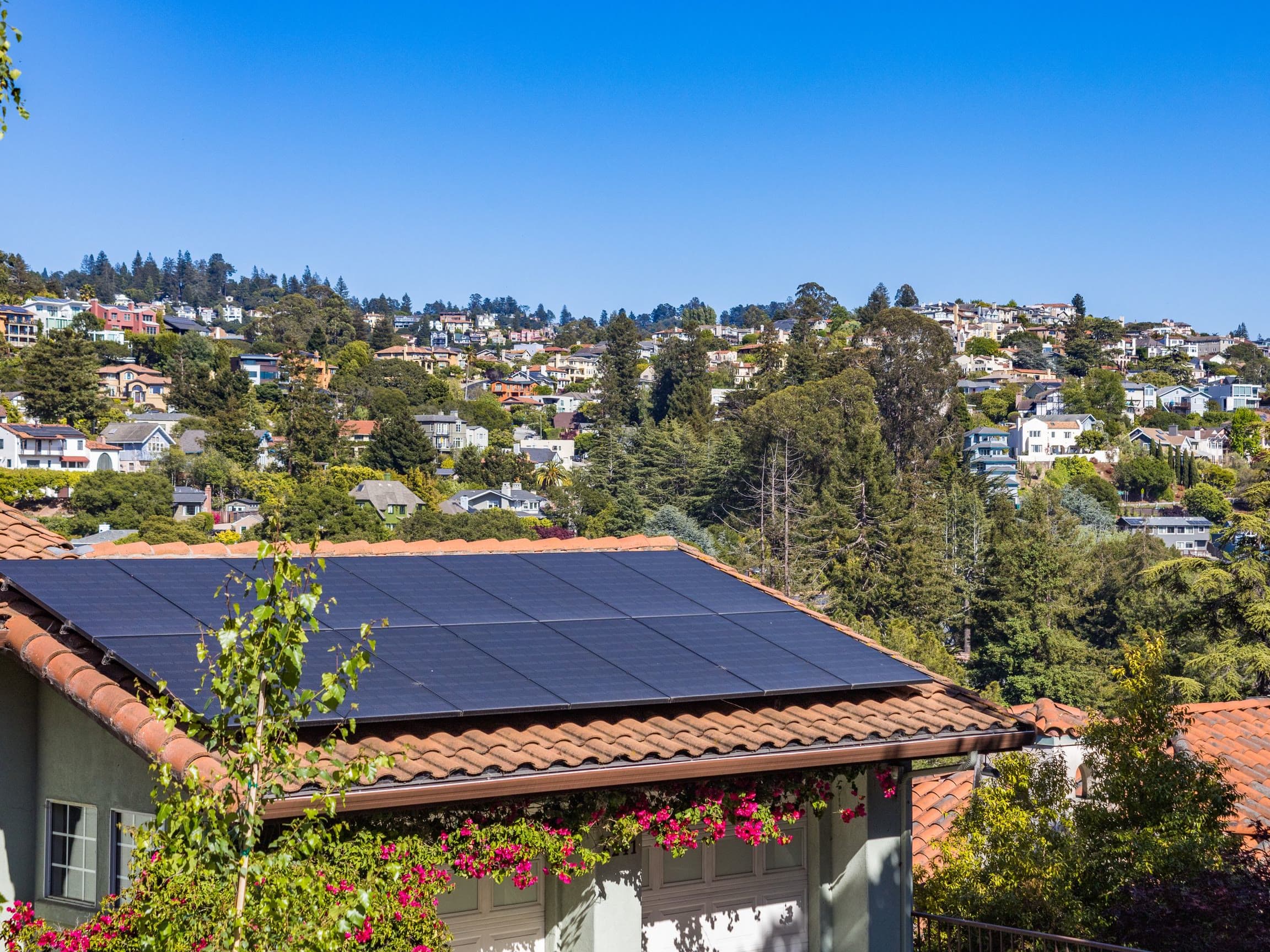 Solar panels on the tiled roof of a hillside home on a sunny day